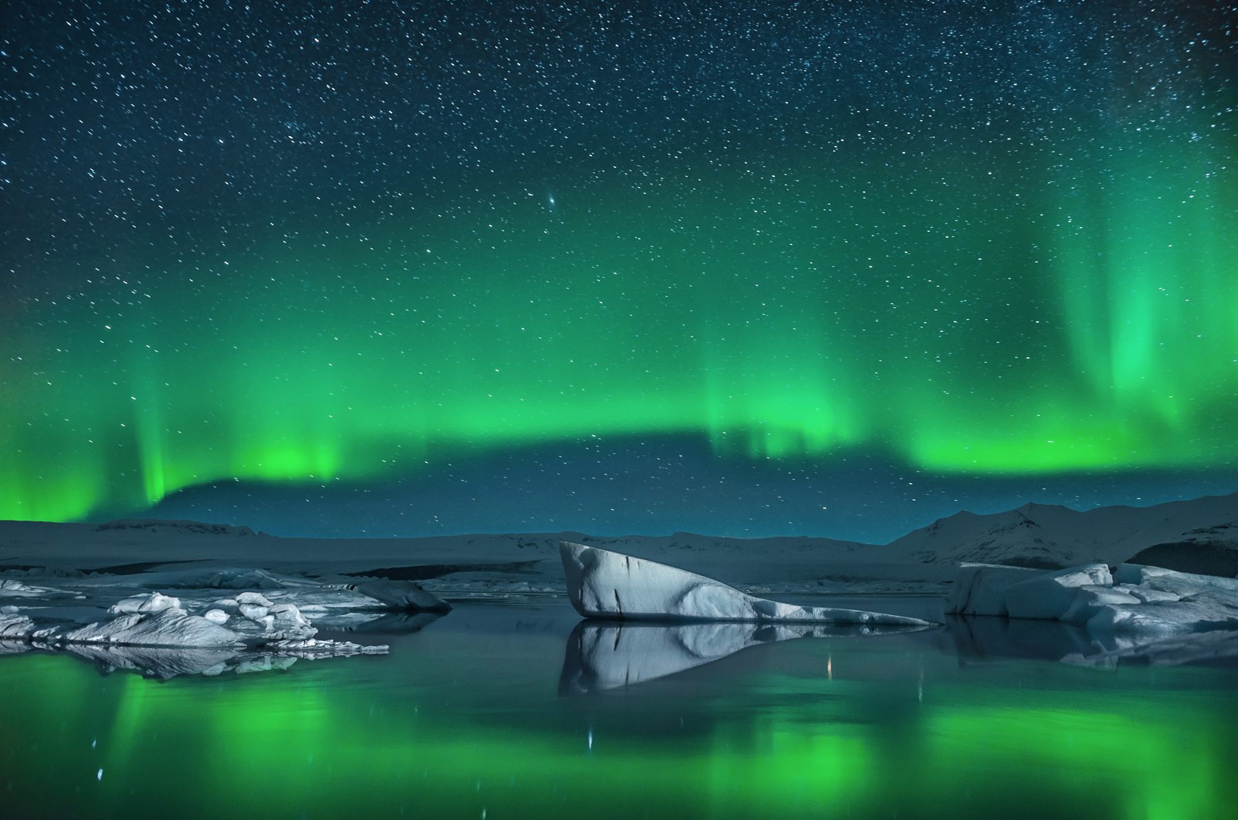 Green northern lights over floating icebergs at Jökulsárlón lagoon, Iceland